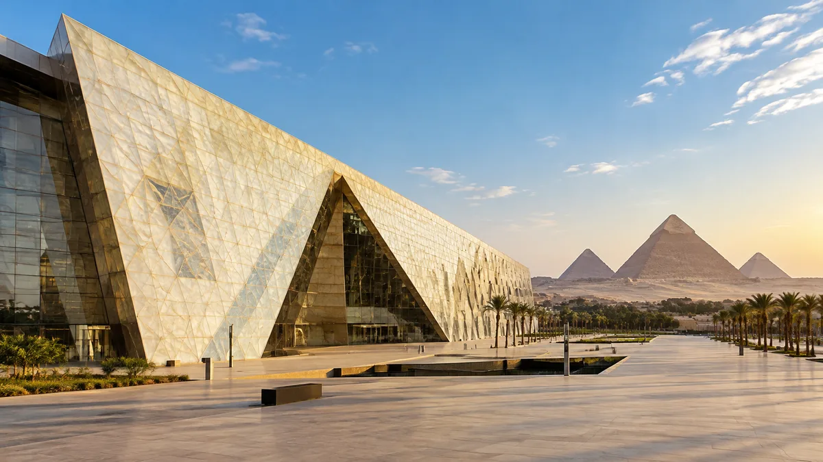 A huge modern museum with a slanted pale facade and the Giza pyramids on the horizon