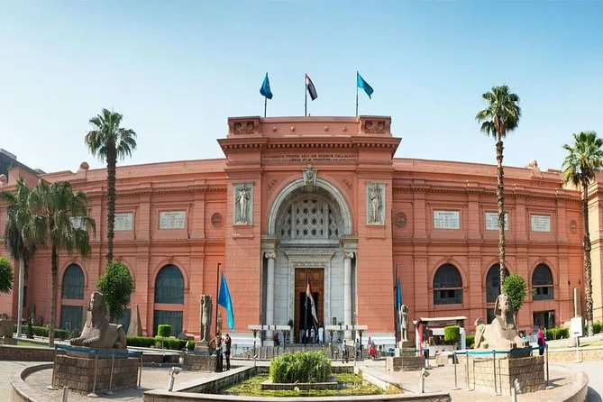 The salmon-red facade of the Egyptian Museum on Tahrir Square behind its front garden and palm trees